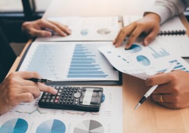 Resize of business-people-analyzing-summary-graph-reports-of-2022-12-16-03-35-51-utc Two business people analyzing summary graph reports of business operating expenses and using calculator profit calculation in the office.