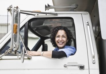 Hispanic woman truck driver and company delivery truck. Hispanic woman truck driver and company delivery truck.