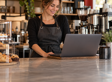 Café owner using a laptop at the counter of her business